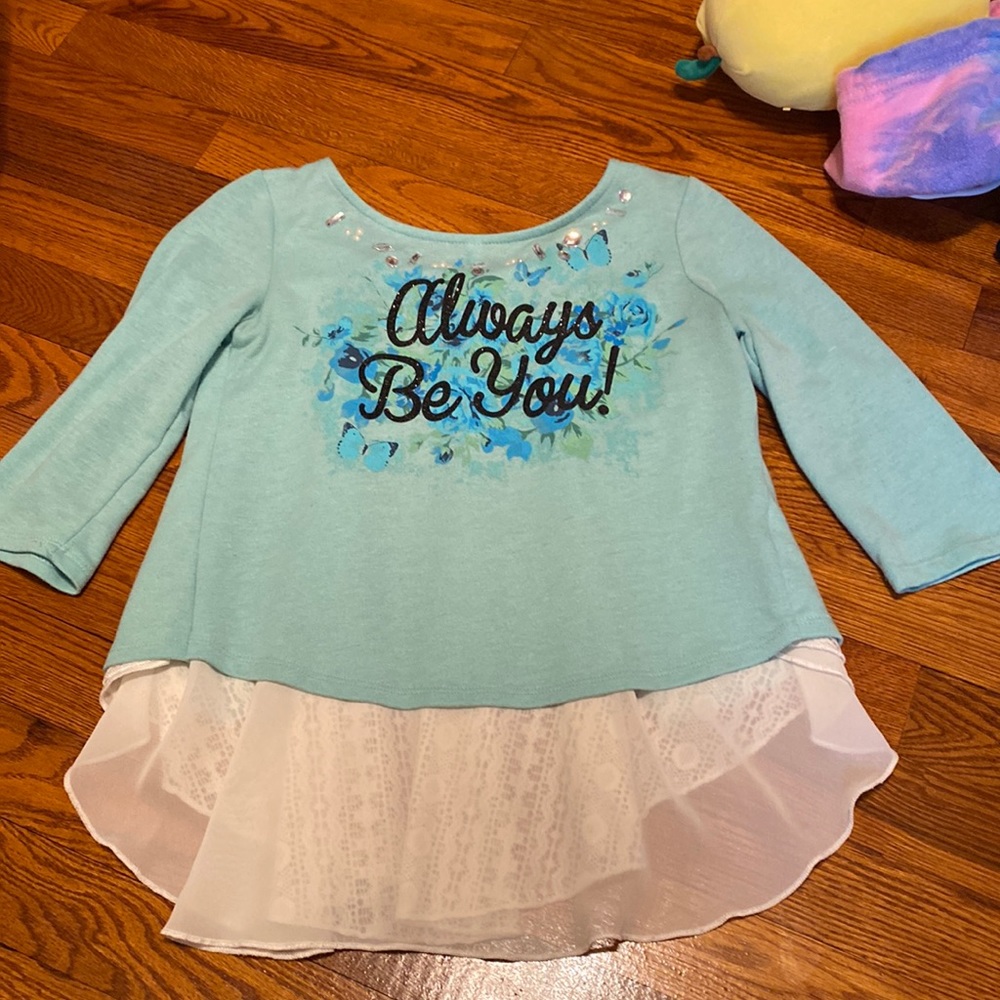 Light blue shirt with butterflies and flowers. Says “Always be you!”